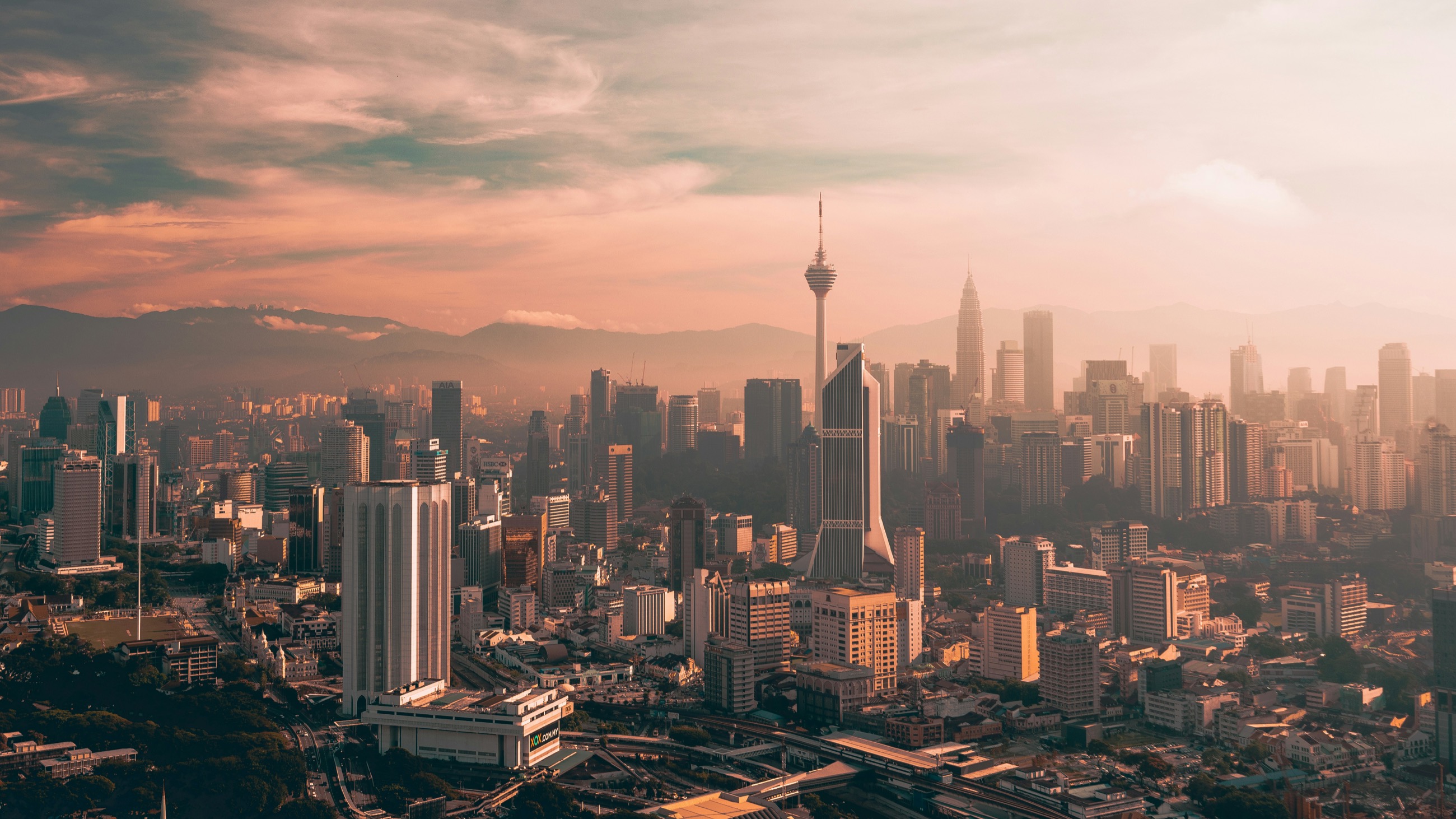 The Kuala Lumpur skyline at dawn, with the KL Tower and distant mountains